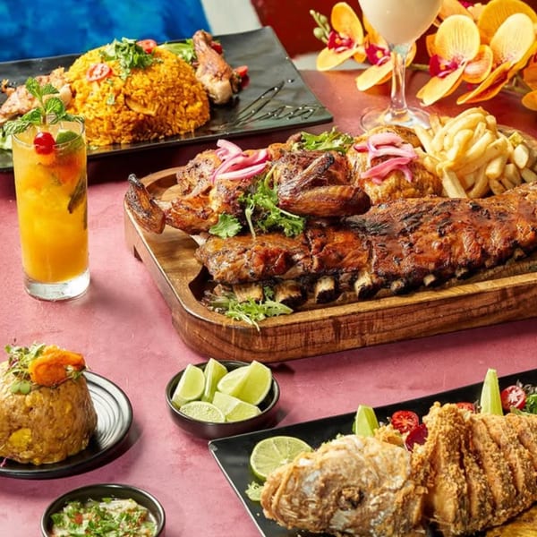 A vibrant spread of Dominican dishes, including roasted meats, rice, fried fish, and cocktails.